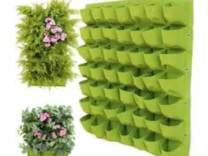 A green planting bag filled with growing flowers.